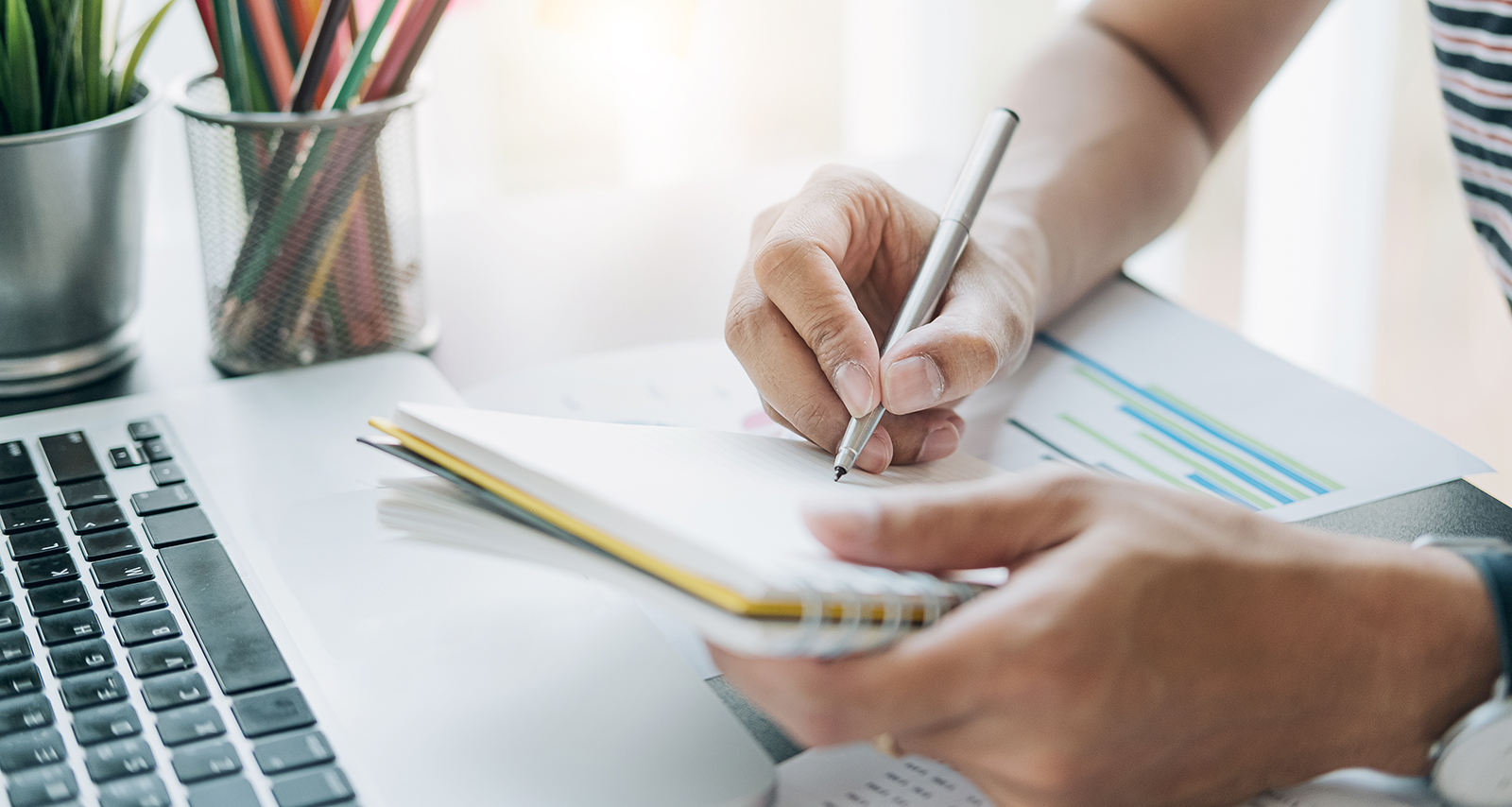 close up of man writing on notepad working